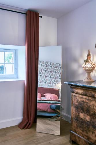 a mirror in a room with a bed and a window at Château Montagne "Terre de Sienne" in Saint-Philippe-dʼAiguille