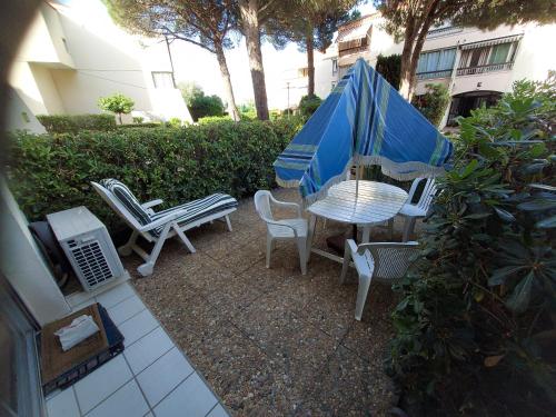 un patio avec une table, des chaises et un parasol dans l'établissement Résidence BORA BORA, à Marseillan