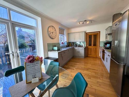 a kitchen with a table and chairs and a clock on the wall at Freeman Hot Tub House, Free Parking, Transport Links in Longbenton