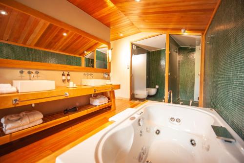 a bathroom with a tub and a sink and a mirror at Uman Lodge Patagonia Chile in Futaleufú