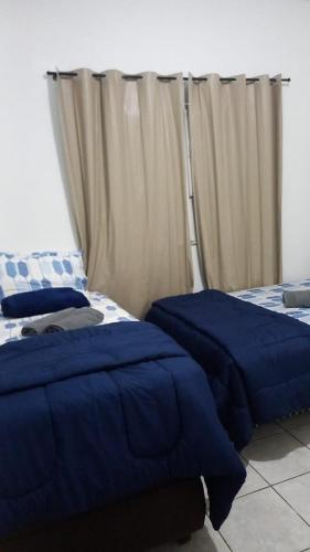 2 camas con sábanas azules en una habitación con cortinas en my sweet place 4, en São Luís