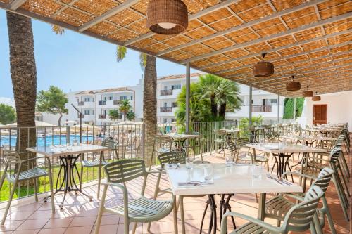 an outdoor patio with tables and chairs and a pool at Inturotel Cala Azul in Cala d´Or