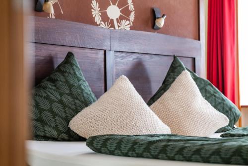 a bed with green pillows and a wooden headboard at Landhaus Wern's Mühle in Ottweiler