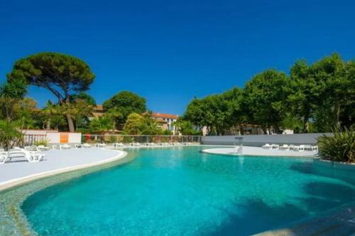 - une piscine avec des chaises blanches et des arbres dans l'établissement Mobile Home Camping Parc des Sept Fonts B255, à Agde