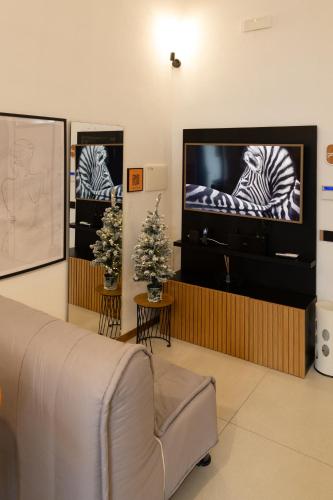 a living room with a flat screen tv and a couch at Dislocati BnB - Jacuzzi privata - Cucina - TV60" - Minimal Luxury in Marigliano