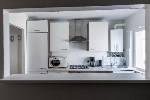 une cuisine blanche avec des armoires blanches et un micro-ondes dans l'établissement Hexagone Wifi Un Séjour à Part, à Longeville-lès-Metz