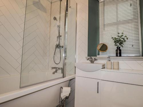 a white bathroom with a shower and a sink at Porter's Lodge in Inverness