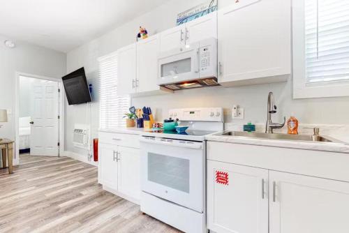 a white kitchen with white cabinets and a sink at Holly's Hideaway - Truman @ Duval Unit D in Key West