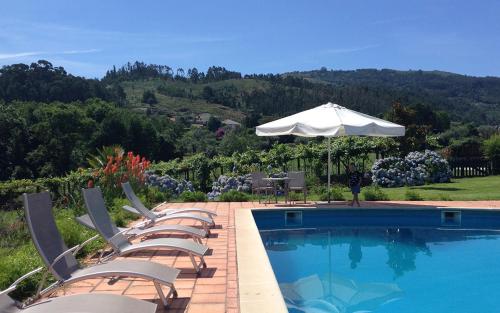 a group of chairs and an umbrella next to a swimming pool at Casa de Abbades in Ponte de Lima