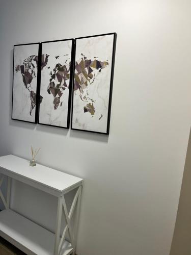 a white table with four pictures on a white wall at Apartman Teona in Novi Sad