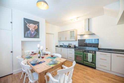 a kitchen with a wooden table and white chairs at Culberry Cottage, Southwold in Southwold