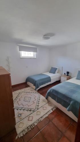 a bedroom with two beds and a rug at Retiro do Viajante in Penacova