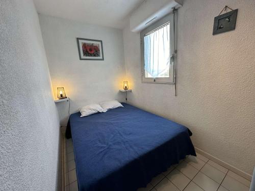 - une petite chambre avec un lit bleu et une fenêtre dans l'établissement Narbonne Plage : Appartement 2 Chambres, Balcon, Ascenseur - FR-1-229B-90, à Narbonne