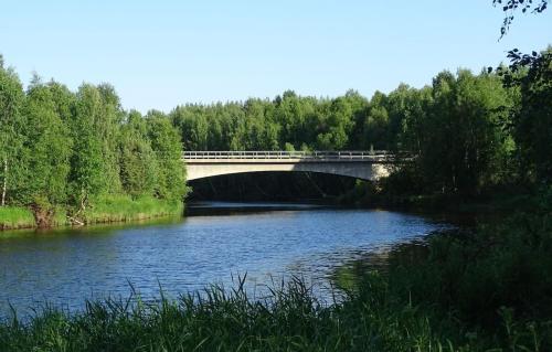 a bridge over a river next to a forest at Humlehjarta Zwei Betten Zimmer in Överkalix