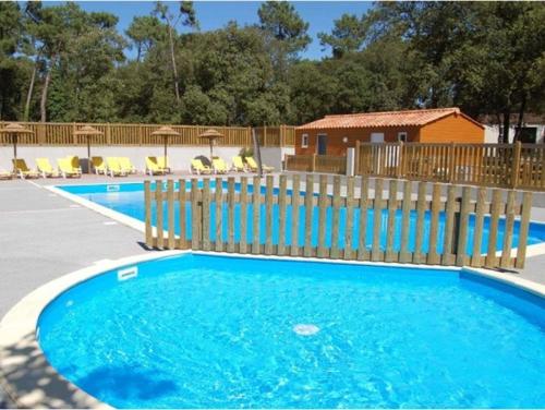 une piscine bleue avec une clôture en bois et des chaises dans l'établissement Camping maeva Respire Parfums d'Eté, à Jard-sur-Mer