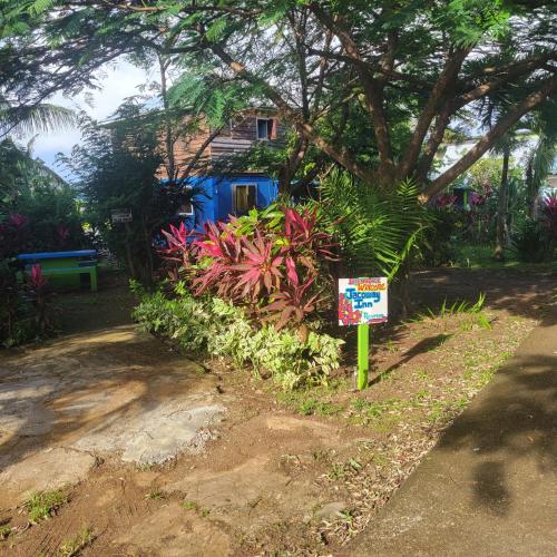 a sign in front of a house with plants at Jacoway Inn in Calibishie