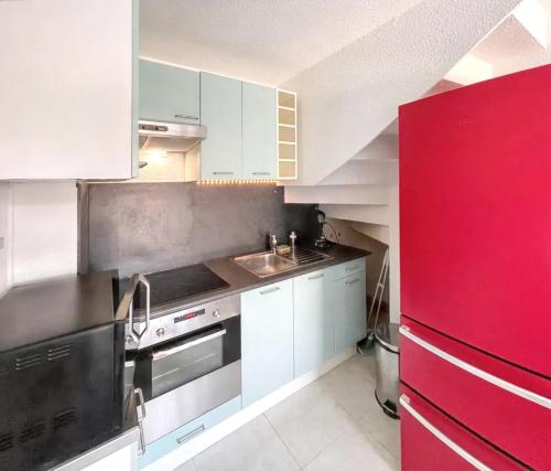 La cuisine est équipée de placards blancs et d'un réfrigérateur rouge. dans l'établissement Maison cosy à La Londe-les-Maures, proche plage, à La Londe-les-Maures