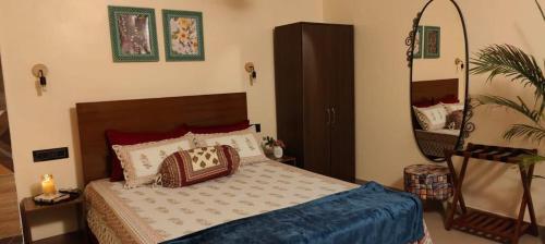 a bedroom with a bed with pillows and a mirror at Paradise Farm Alibaug in Bhāweghar