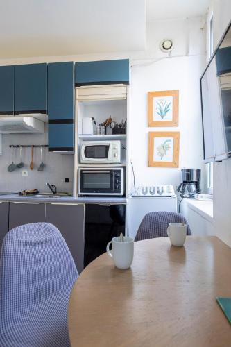 une cuisine avec une table en bois et des armoires bleues dans l'établissement Mini Mosaïque Parking Un Séjour à Part, à Longeville-lès-Metz