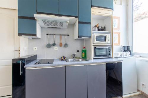 La cuisine est équipée de placards bleus, d'un évier et d'un four micro-ondes. dans l'établissement Mini Mosaïque Parking Un Séjour à Part, à Longeville-lès-Metz