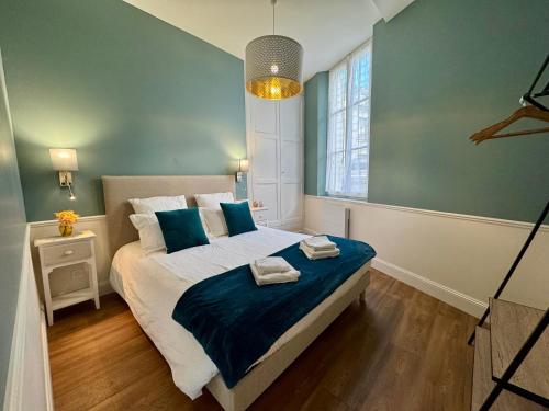 - une chambre dotée d'un grand lit avec des draps bleus et une fenêtre dans l'établissement Centre ville terrasse et vue Château, à Saumur