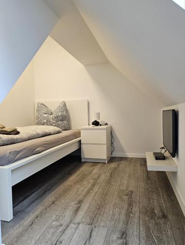 a white bedroom with a bed and a tv at Bördeapartment am Heiderand 2 in Samswegen