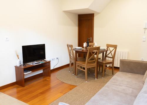 a living room with a table and chairs and a television at Cabo do Mar Apart.- Sereias Beach in Espinho