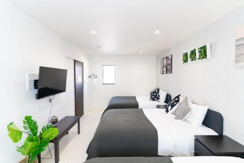 a bedroom with two beds and a flat screen tv at Shirara Terrace B in Shirahama
