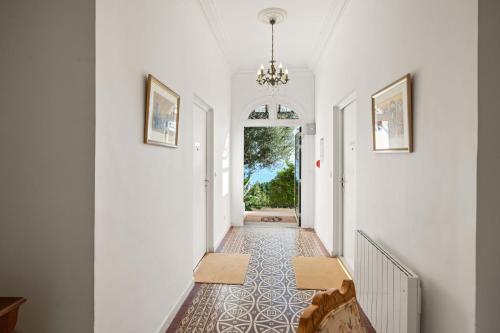 a hallway with white walls and a chandelier at Hôtel Le Roquebrune in Roquebrune-Cap-Martin