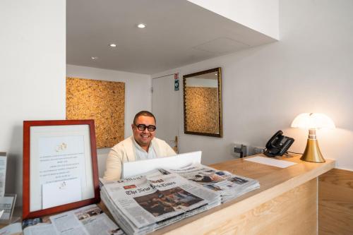 a man sitting at a desk with a newspaper at Hôtel Le Roquebrune in Roquebrune-Cap-Martin