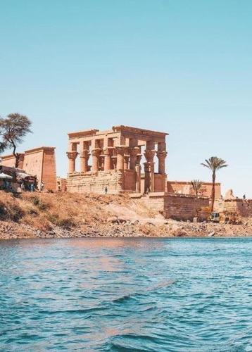 um edifício sobre uma colina ao lado de um corpo de água em 4 Days Nile Cruise from Luxor to Aswan em Luxor