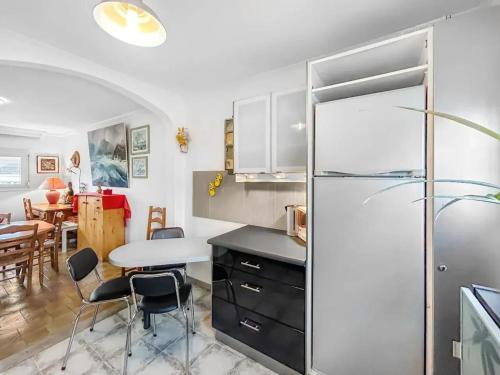 Il comprend une cuisine équipée d'un réfrigérateur et d'une table avec des chaises. dans l'établissement Maison charmante à Saint-Herblain avec jardin privé, à Saint-Herblain