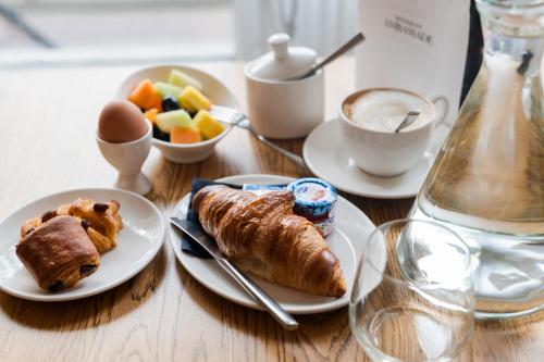 a wooden table topped with plates of food and fruit at Ambassade Hotel in Amsterdam