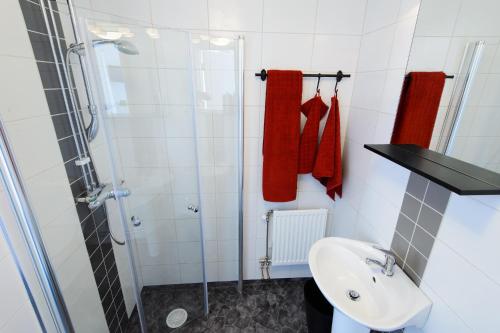 a bathroom with a sink and a shower with red towels at Knutes pensionat in Svansele