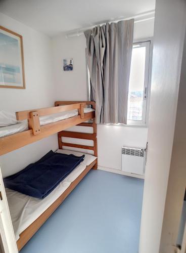 une chambre avec deux lits superposés et une fenêtre dans l'établissement appartement en frond de mer, à Soulac-sur-Mer