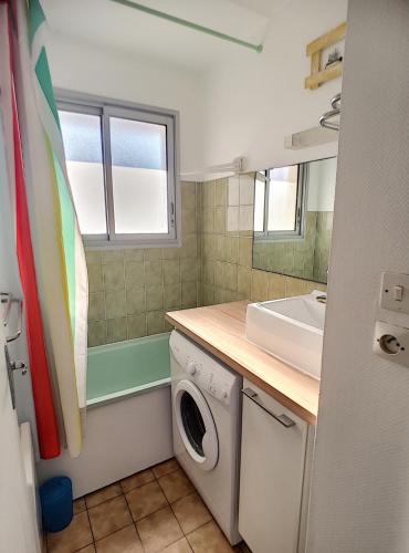 une salle de bain avec une machine à laver et un lavabo dans l'établissement appartement en frond de mer, à Soulac-sur-Mer