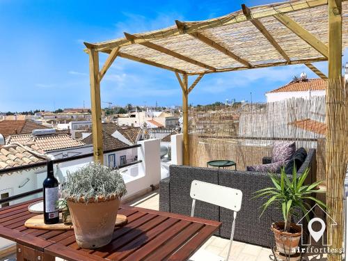 a balcony with a wooden table and a pergola at Casa Castelo, Unique Flat w pool in Taviras Historical Centre in Tavira