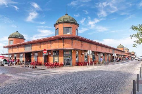 a large brick building with a clock tower on a street at Casa Alice - Olhão in Olhão