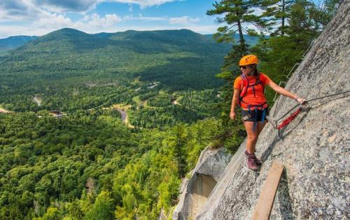 a person standing on a rock on a cliff at Magnifique VUE LAC et SKI in Mont-Tremblant