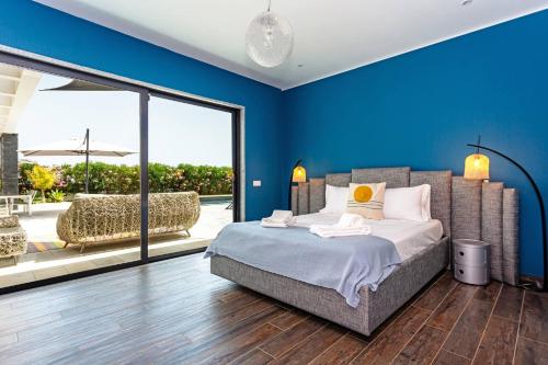 a bedroom with blue walls and a bed and a patio at Blue Hill Boutique Villa by Junto ao Mar in Quelfes