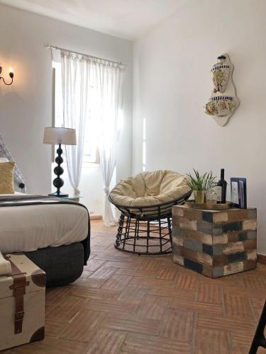 a bedroom with a bed and a chair and a window at Chic Suite Sequa in Taviras Historical Centre in Tavira