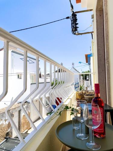 a table with wine glasses on a balcony at Chic Suite Figueiras w balcony in Taviras Historical Centre in Tavira