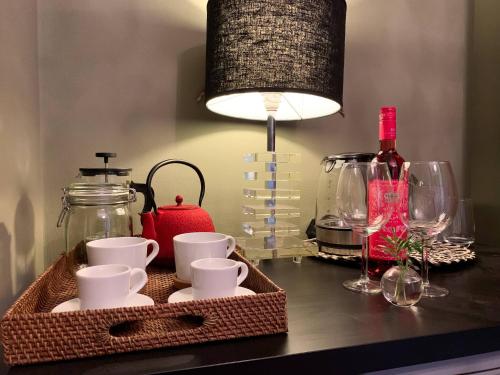 タヴィラにあるChic Suite Figueiras w balcony in Taviras Historical Centreのテーブルとランプの上にカップとグラスを並べたトレイ