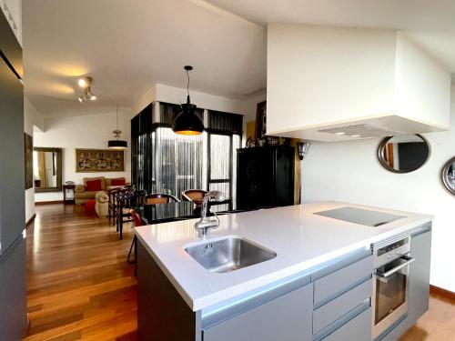 a kitchen with a sink and a living room at Ático en Plaza de la Constitución 3 bedrooms in Málaga
