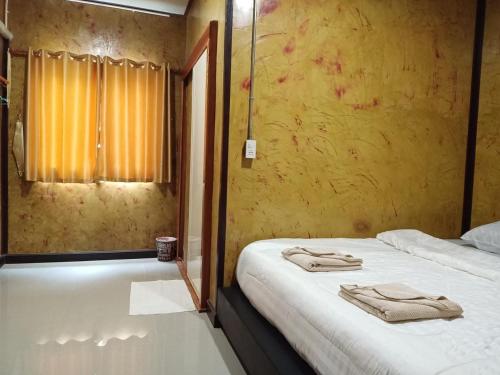 a bedroom with two beds and a window with towels at Libong de loft ลิบงเดอลอฟท์ in Ko Libong