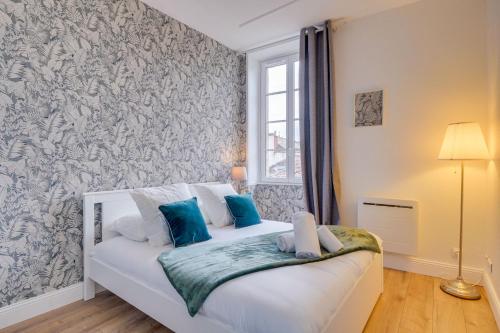 une chambre avec un lit blanc avec des oreillers bleus dans l'établissement Le Sauvage - Au coeur du quartier St Pierre, à Bordeaux