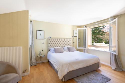 une chambre avec un grand lit et une fenêtre dans l'établissement Maison au calme près de Versailles, à Louveciennes
