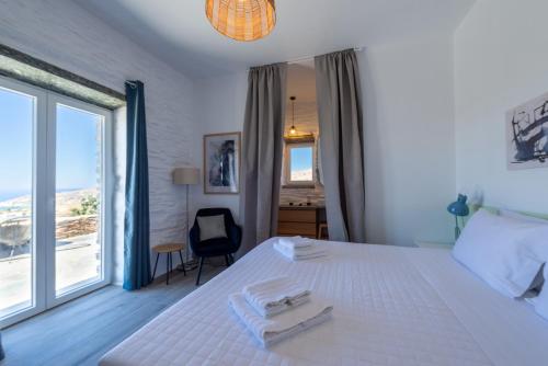 a bedroom with a white bed and a large window at Petra Vista Retreats in Otzias