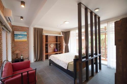 a bedroom with a bed and a red chair at Laoxao RiverStone Villa in Hoi An