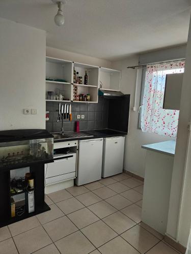 une cuisine avec des armoires blanches, un évier et une fenêtre dans l'établissement Studio avec piscine jardin, à Poussan